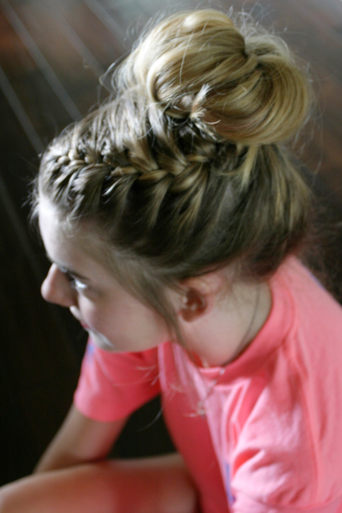 Side view of a girl with blonde hair showing off a side braid and voluminous messy bun.