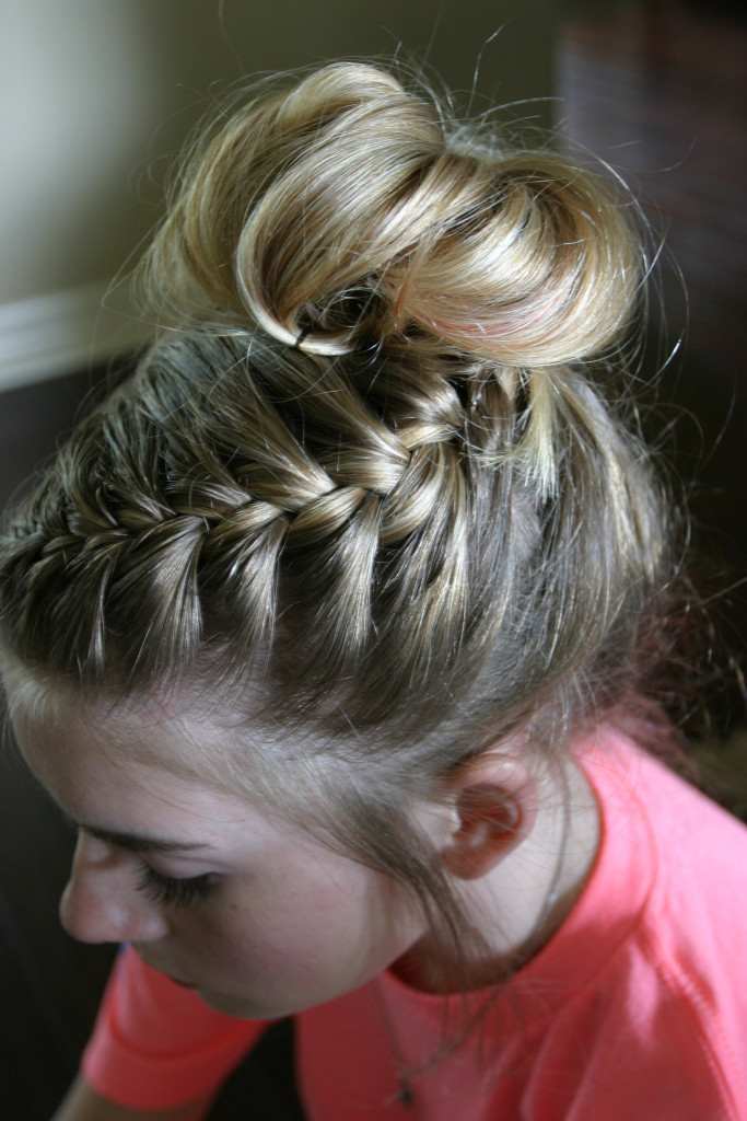 Top left-side angle of a girl's head with intricate braid that ends in a bun on the top of her head.