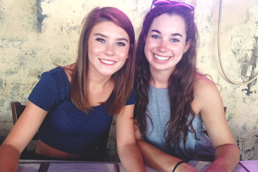 Two young, smiling brunette girls awaiting lunch at Hueys on River Street in Savannah GA.