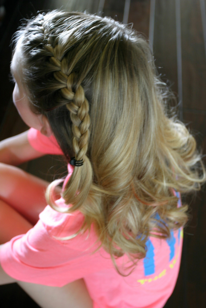 Girl with loosely curled long blonde hair and a side braid.