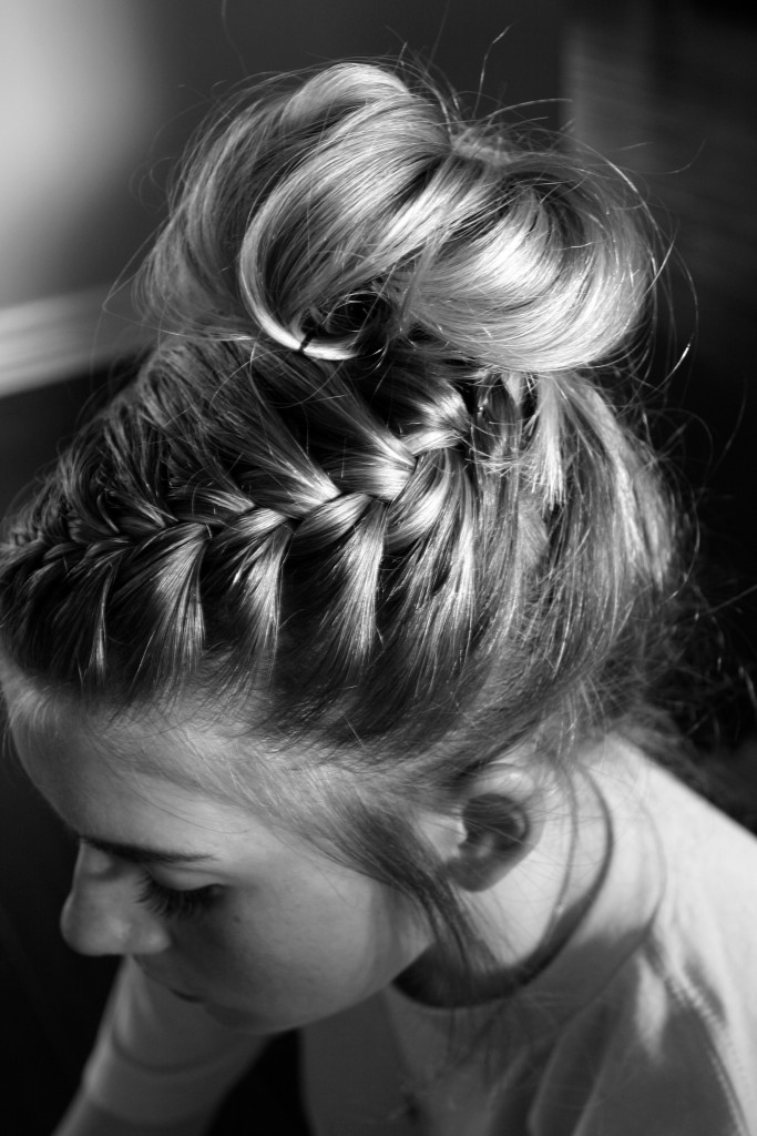 B&W image of a girl with a side braid that ends in a messy bun piled atop her head.