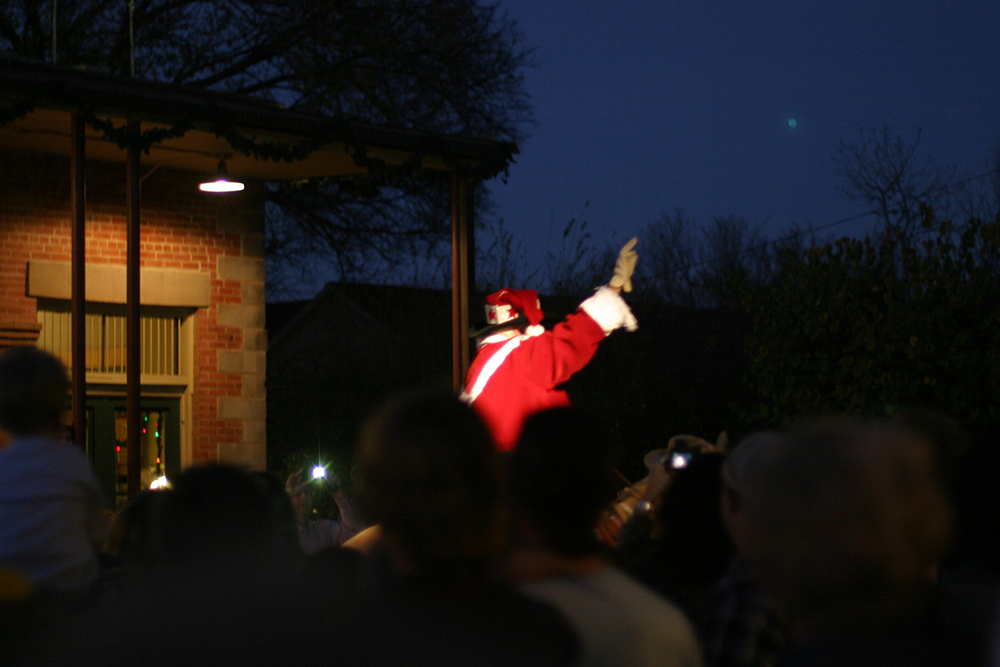 Cowboy Kringle waves at the crowd as he rides into town after sunset.