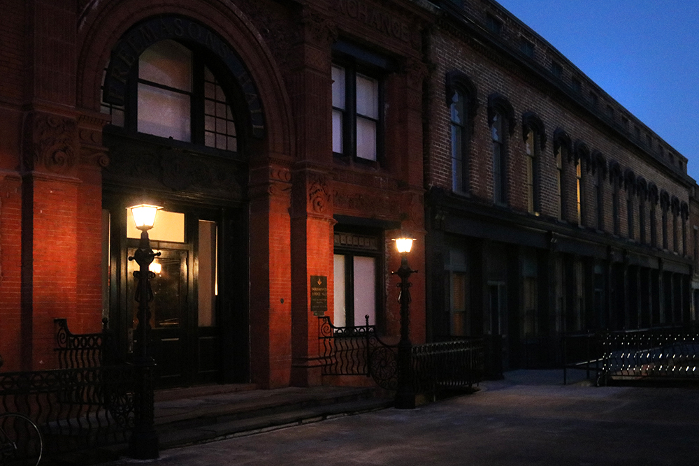 The dimly lit historic Cotton Exchange Building on River Street in Savannah looks rather mysterious at night with its oversized arched black iron entrance and rows of darkened windows.