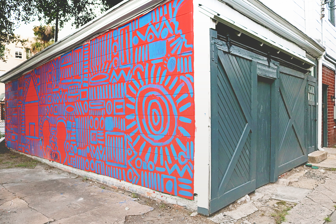 Exterior wall of a building painted with navy and red tribal symbols.