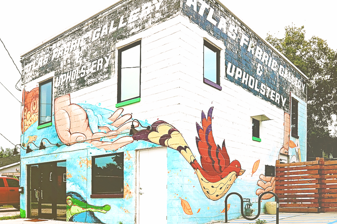 A colorful mural of showing a bird and nature scenes wraps three sides of a yoga studio in Savannah.