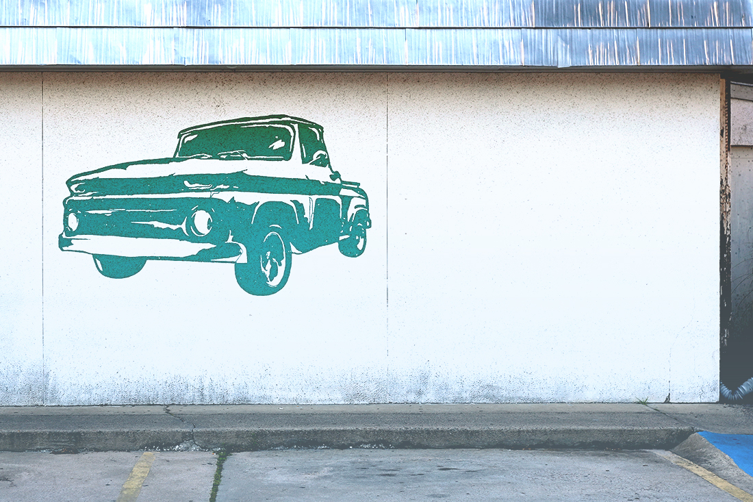 Mural of an old-timey green truck painted on a white wall.