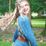 Girl twirling in blue peasant dress with long hair flipping out over her shoulders