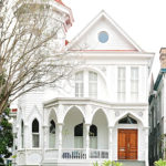 Three-story white Victorian home with an arched porch trim and a turreted roofline.
