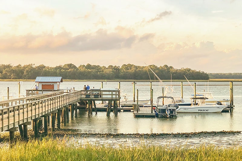 Long wooden pier leading to pink and yellow sunset on Hilton Head Island's Skull Creek.