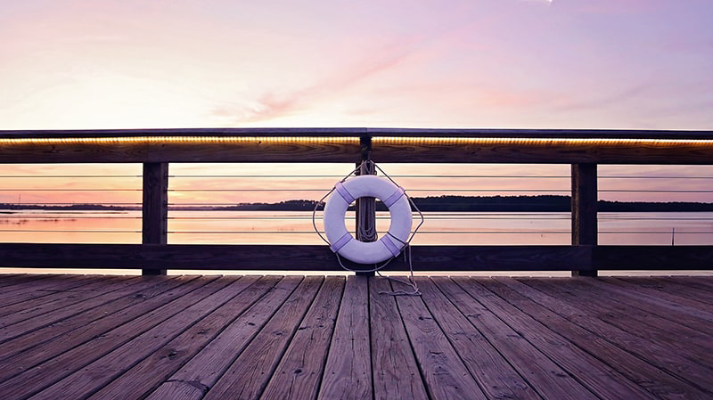 Purple and orange sunset viewed from the deck of a wooden pier at Squire Pope Community Park in Hilton Head.