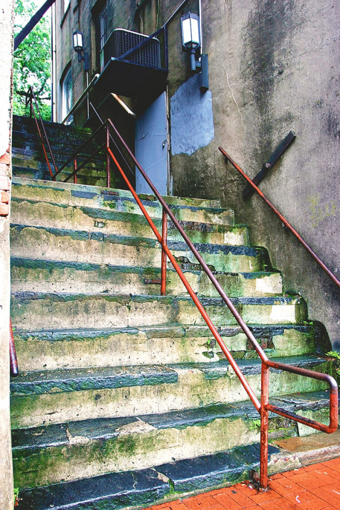 Extremely steep stairs covered with missing chunks and treads covered in green moss.